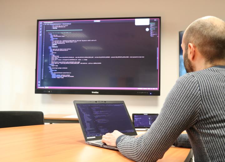 Photo de dos d'un développeur web TIMCOD qui tape des lignes de codes sur son ordinateur 